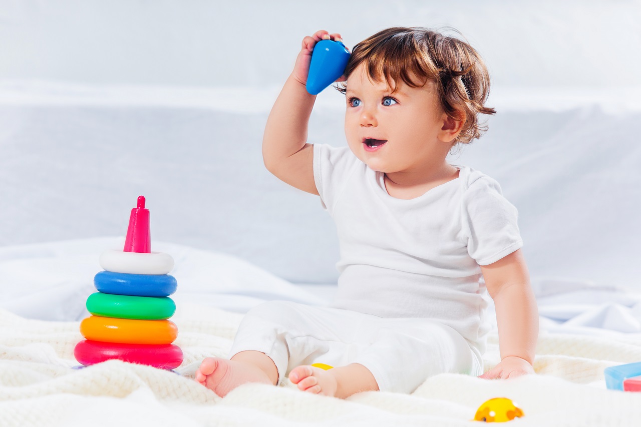 a baby boy sitting on the floor playing with plastic ring toys