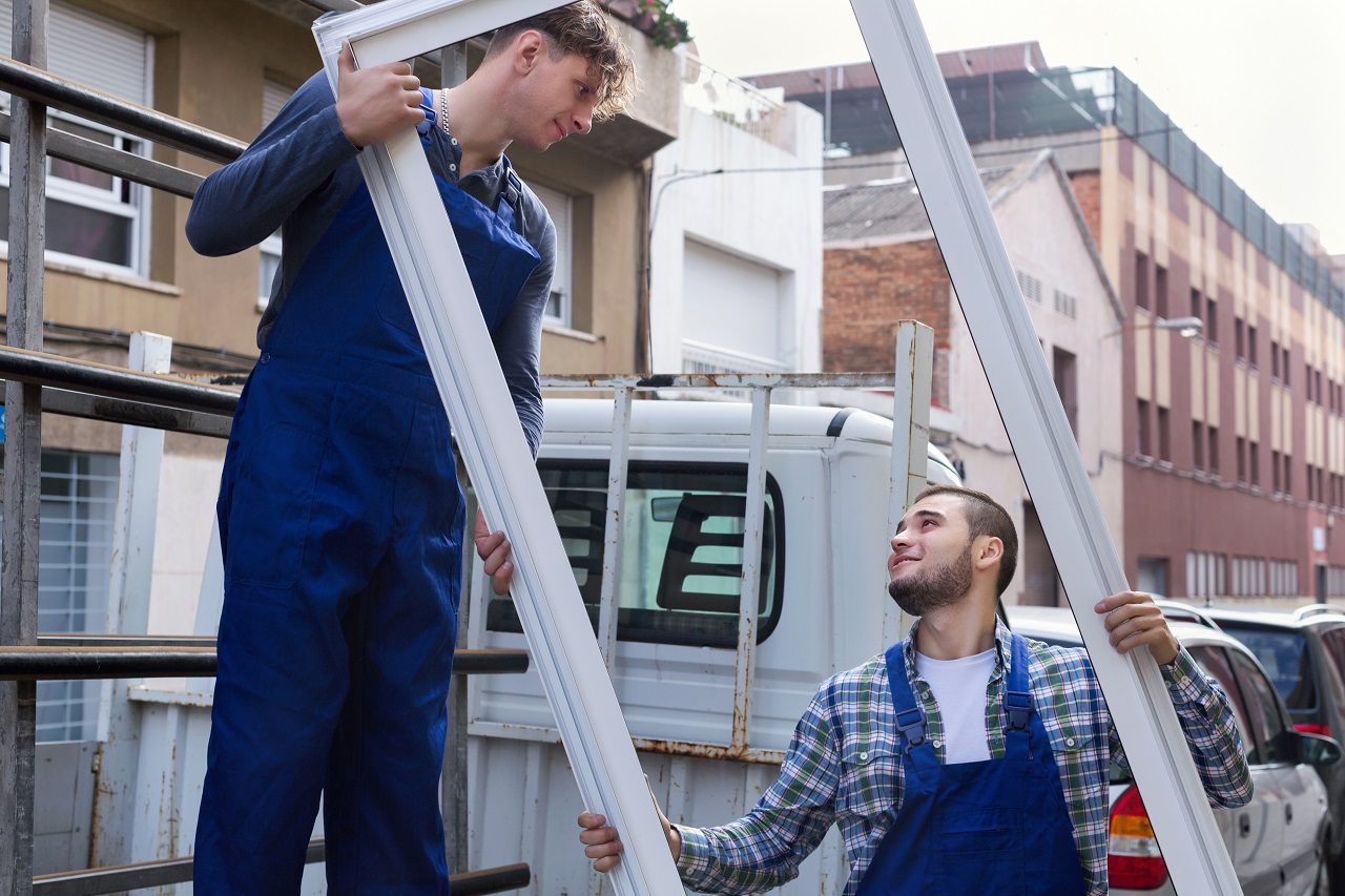 Two workers loading a plastic door frame to a truck