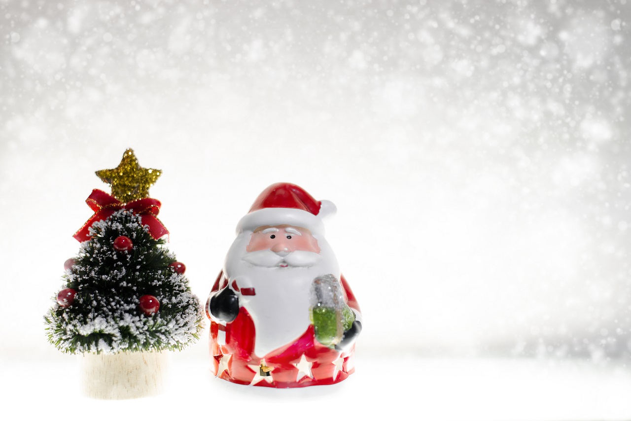 A small plastic santa claus beside a christmas tree