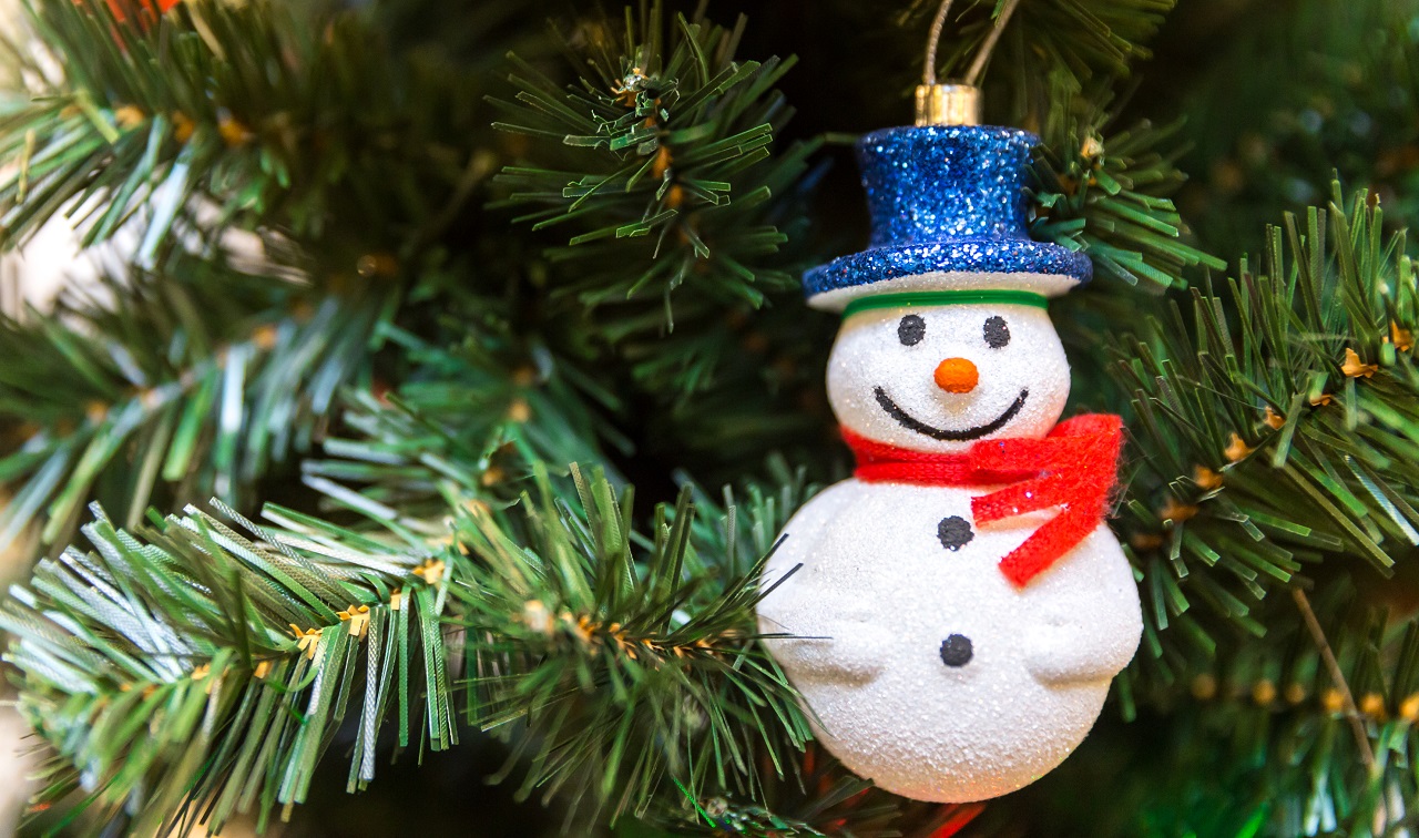 A plastic snowman ornament hung on a Christmas tree