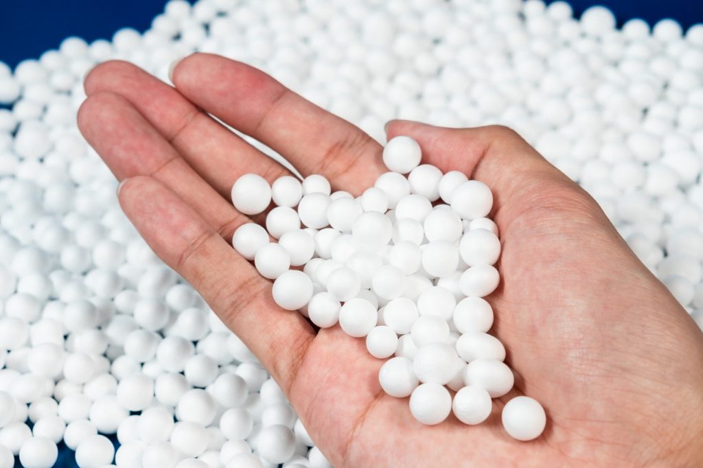 A hand holding white plastic pellets