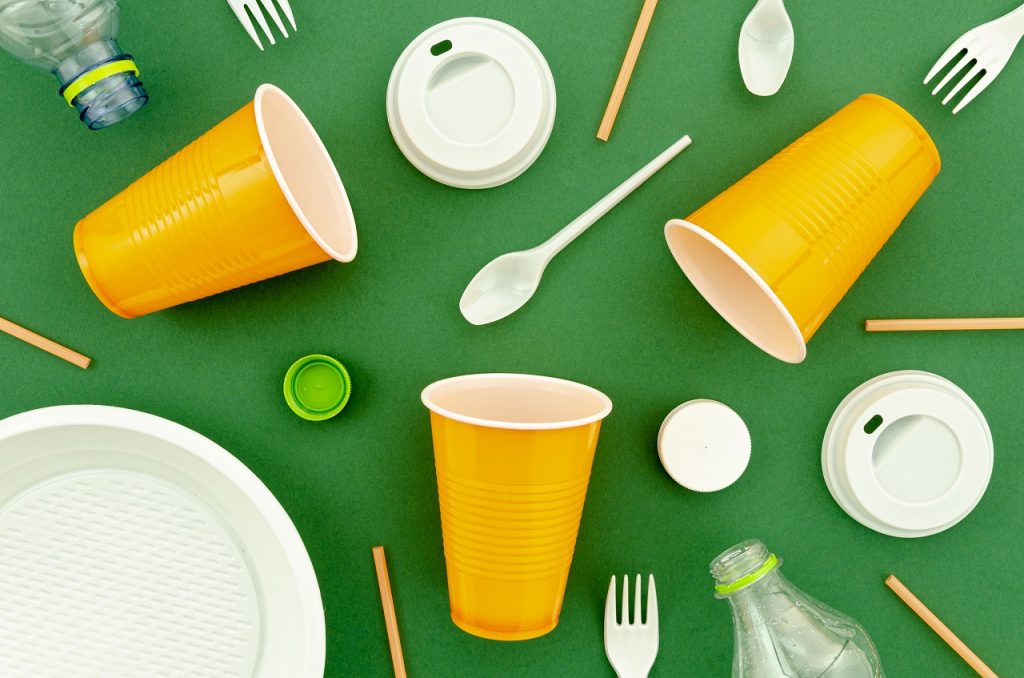 Plastic cups, covers, and utensils on a green background