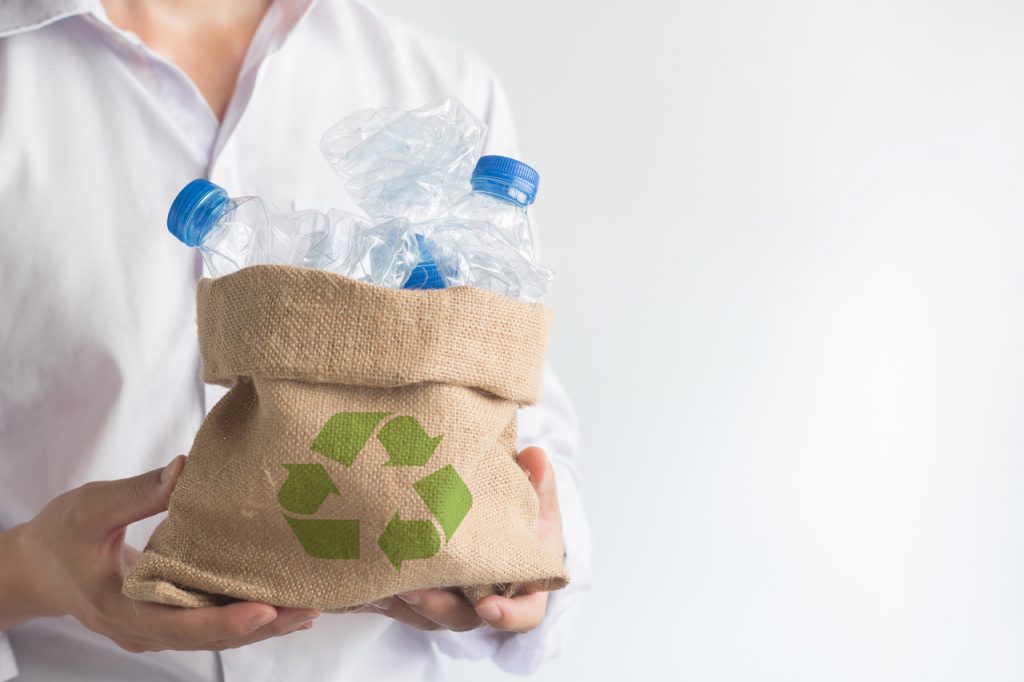 A man holding a bag of plastic bottles for recycling
