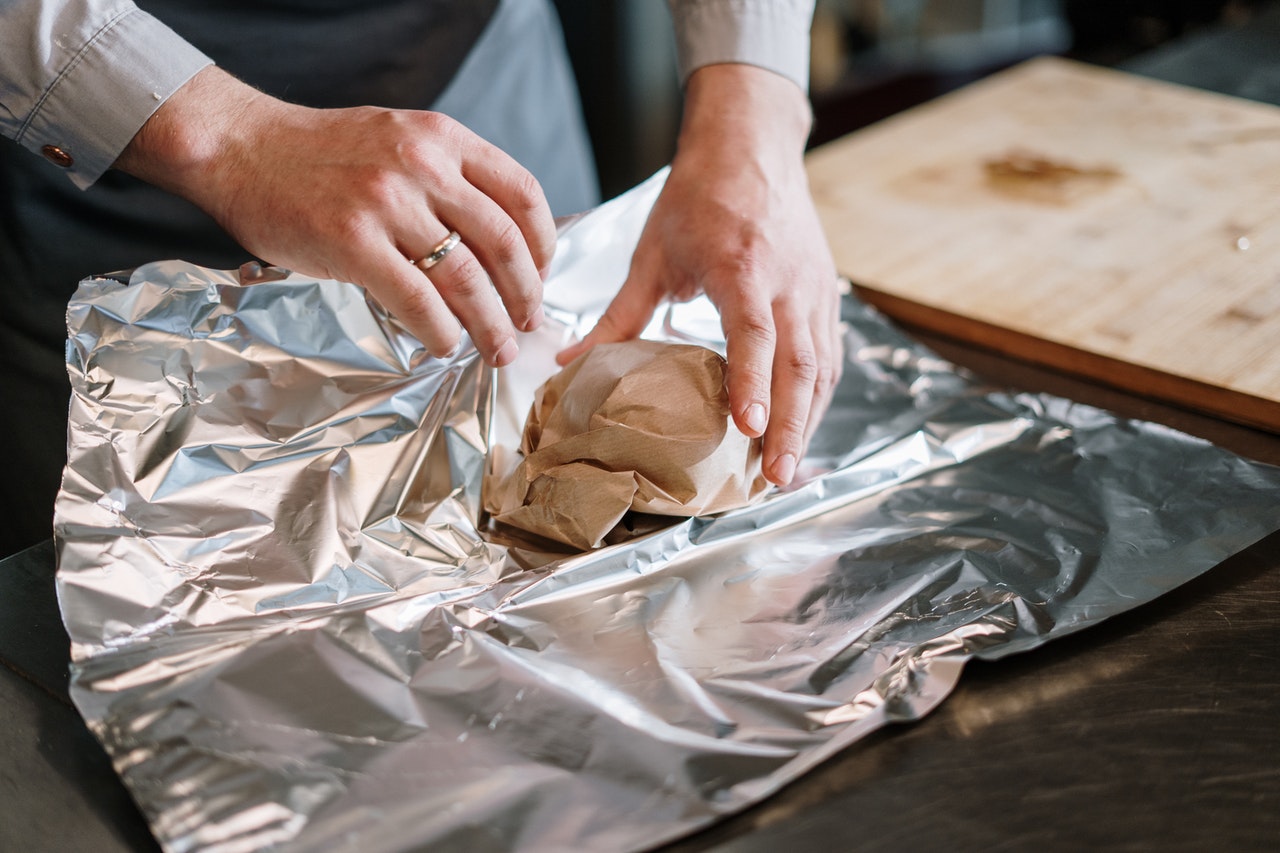 A man struggling to wrap food in tin foil