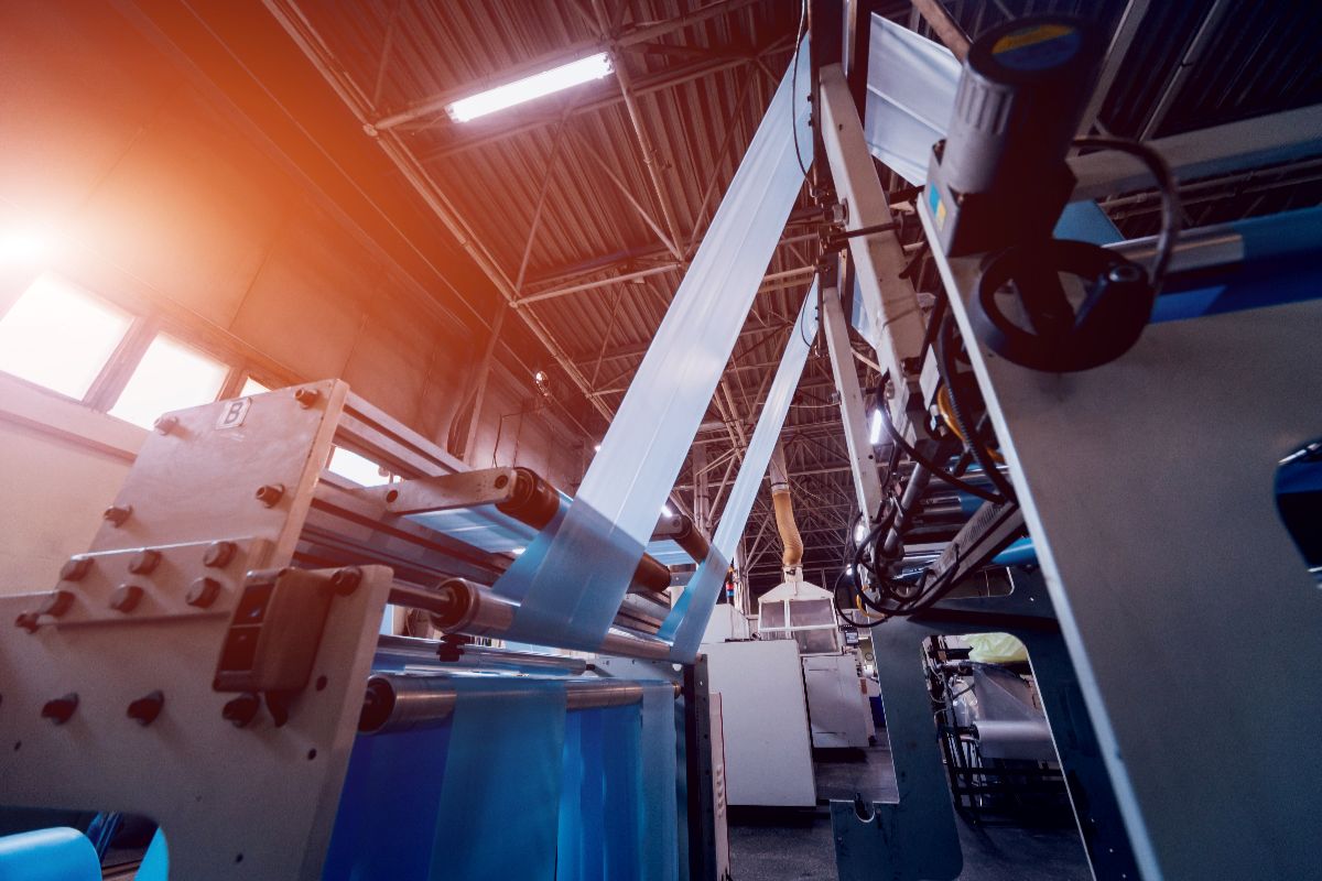 Plastic film production machinery operating inside an industrial manufacturing facility with automated processing equipment.