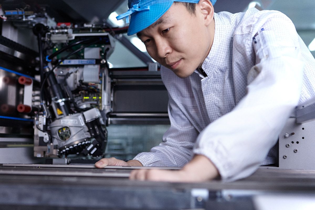 Factory technician inspecting precision manufacturing equipment inside an automated industrial production facility.