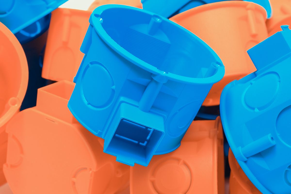 Colorful injection molded plastic electrical box components stacked together for industrial manufacturing applications.