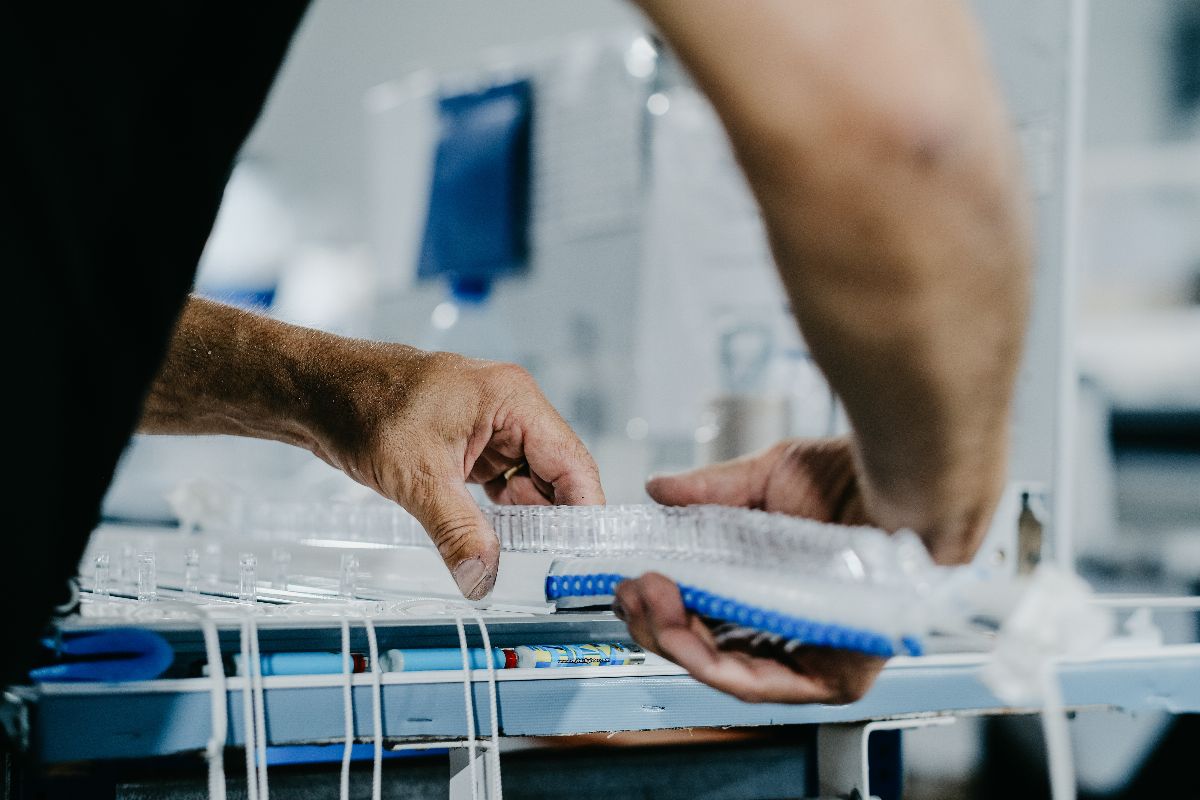 Worker handling clear plastic packaging trays during a plastic manufacturing and assembly process.