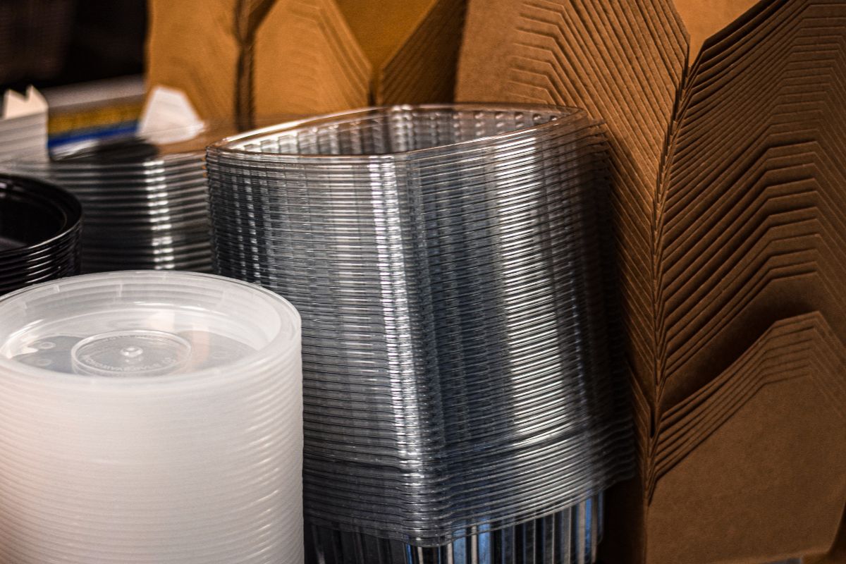 Stacks of clear plastic food containers and packaging materials arranged in a manufacturing facility.