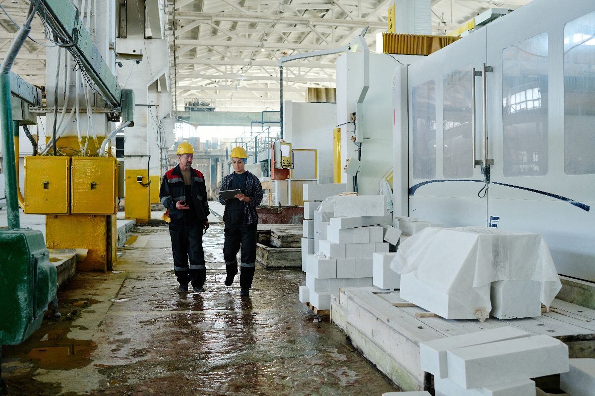 Workers inspecting a large molding production area with industrial machines and equipment