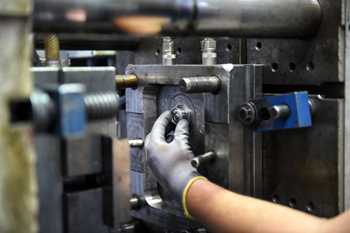 Close-up of a technician adjusting injection mold tooling during production setup