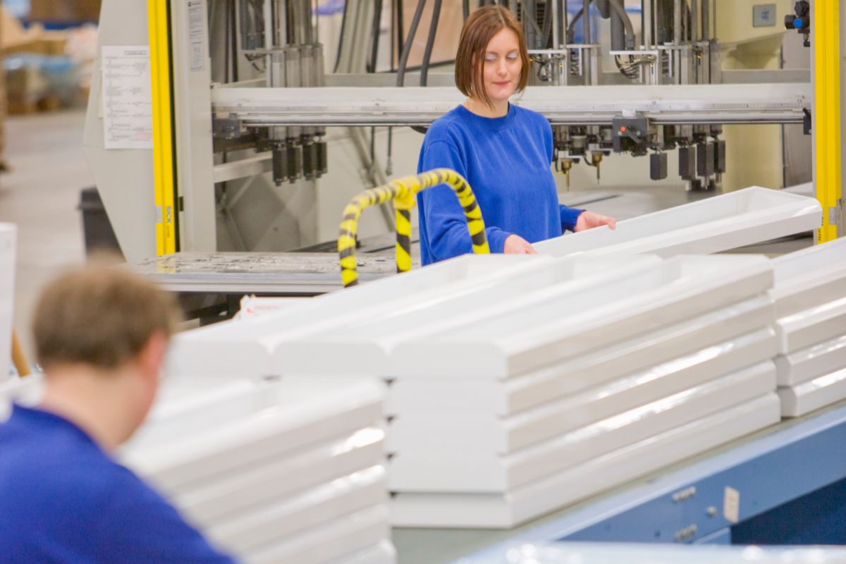 Worker handling large molded plastic components on a production line
