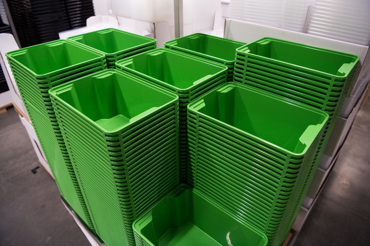 Stacked green molded plastic bins showing consistent production of large plastic components