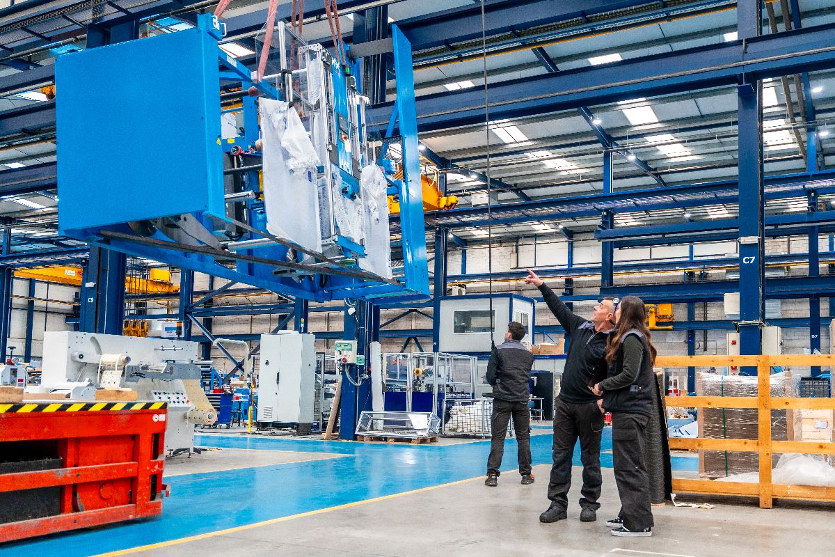 Factory team inspecting large injection molding equipment for high-volume part production